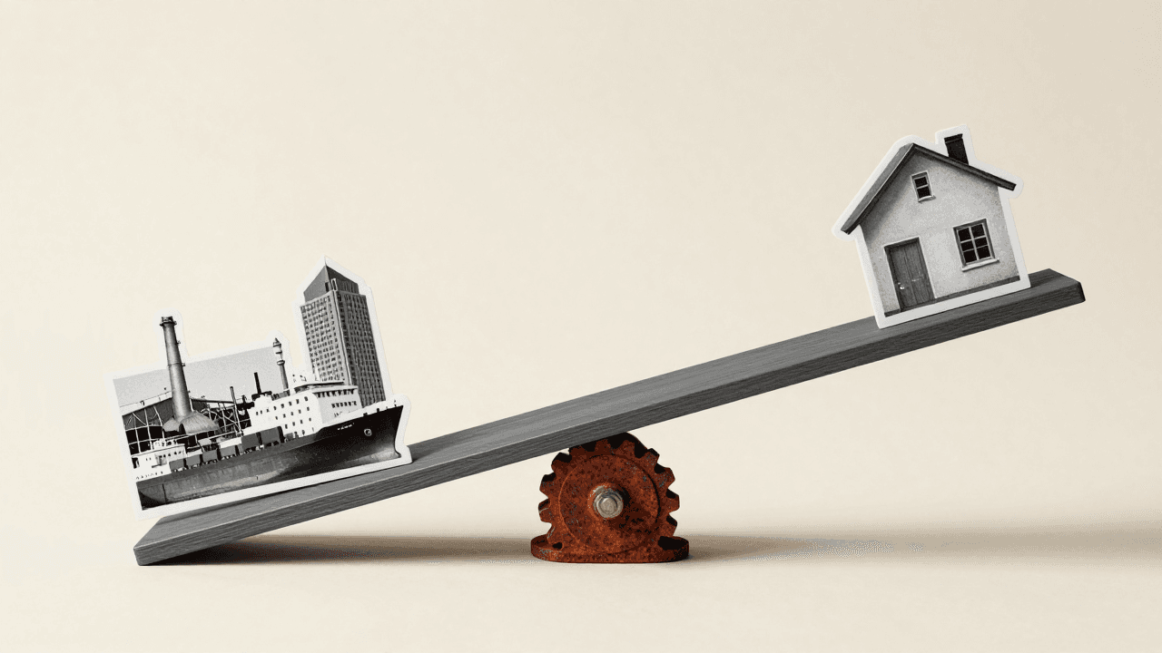 A grey seesaw on a rusted gear, a factory photo cutout on the low end and a small paper house on the high end.